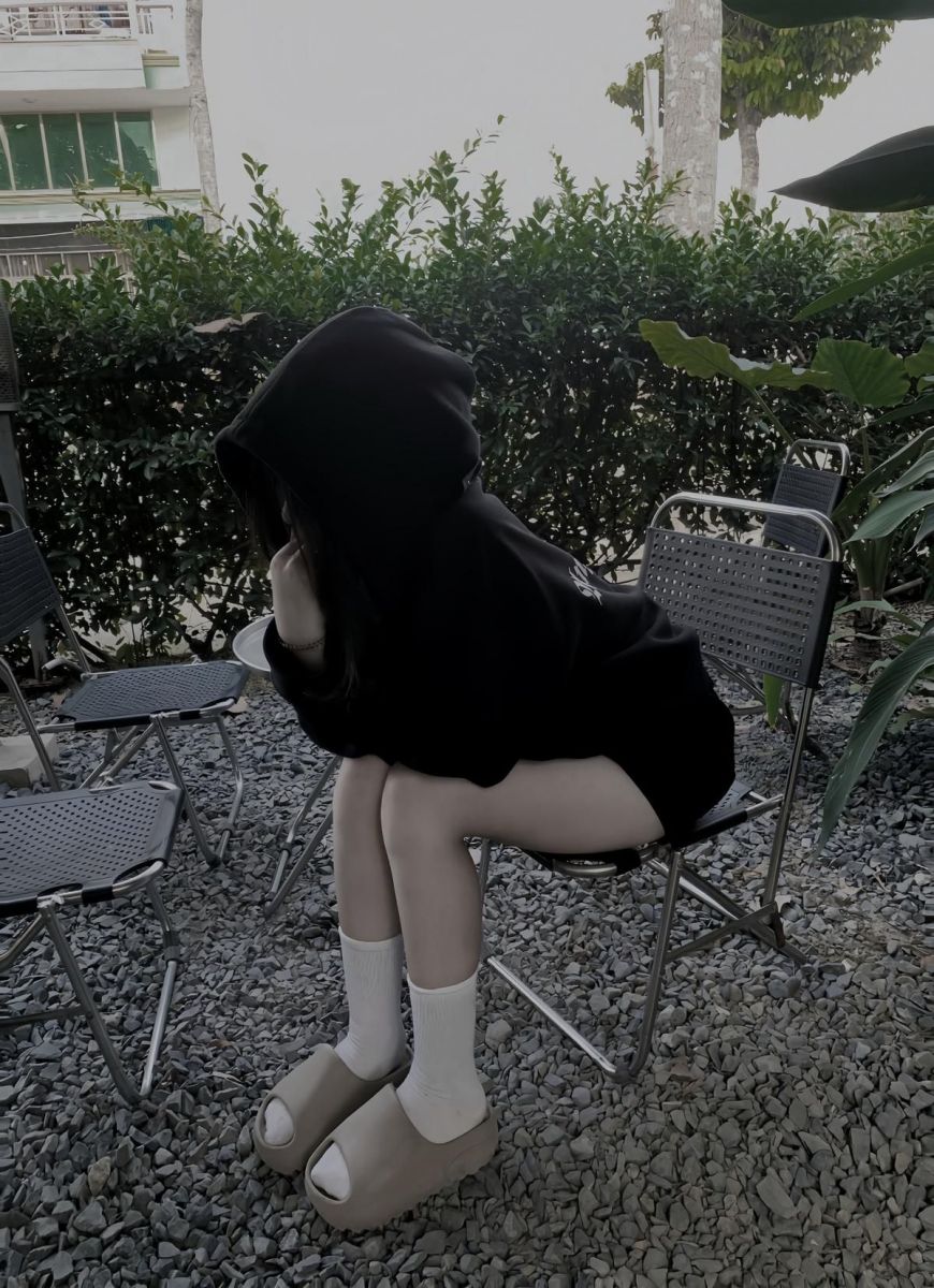 Cô gái xinh không mặc áo hoodie đen khoanh tay trên ghế