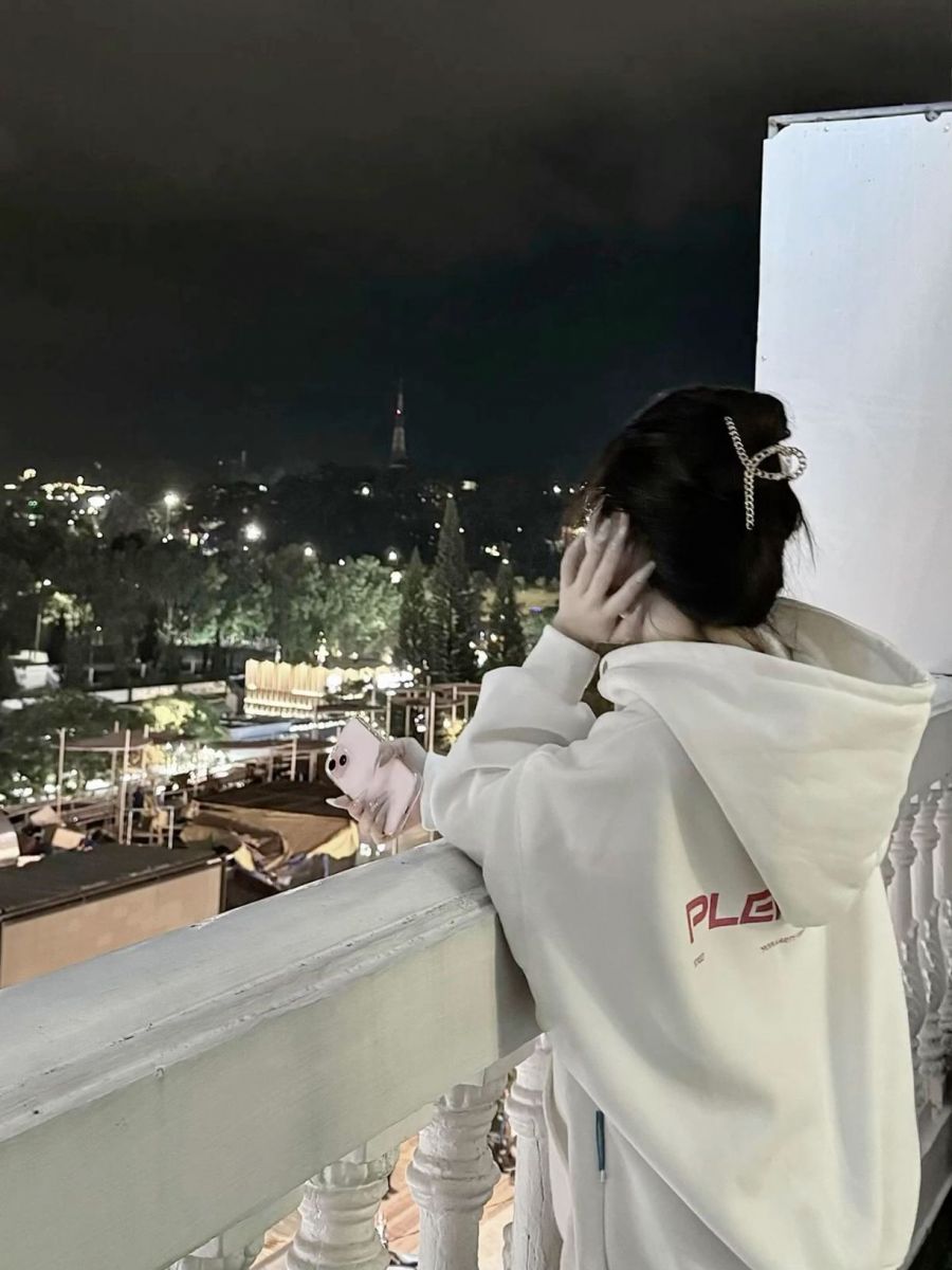 Cô gái xinh mặc áo hoodie trắng ngắm phố đêm