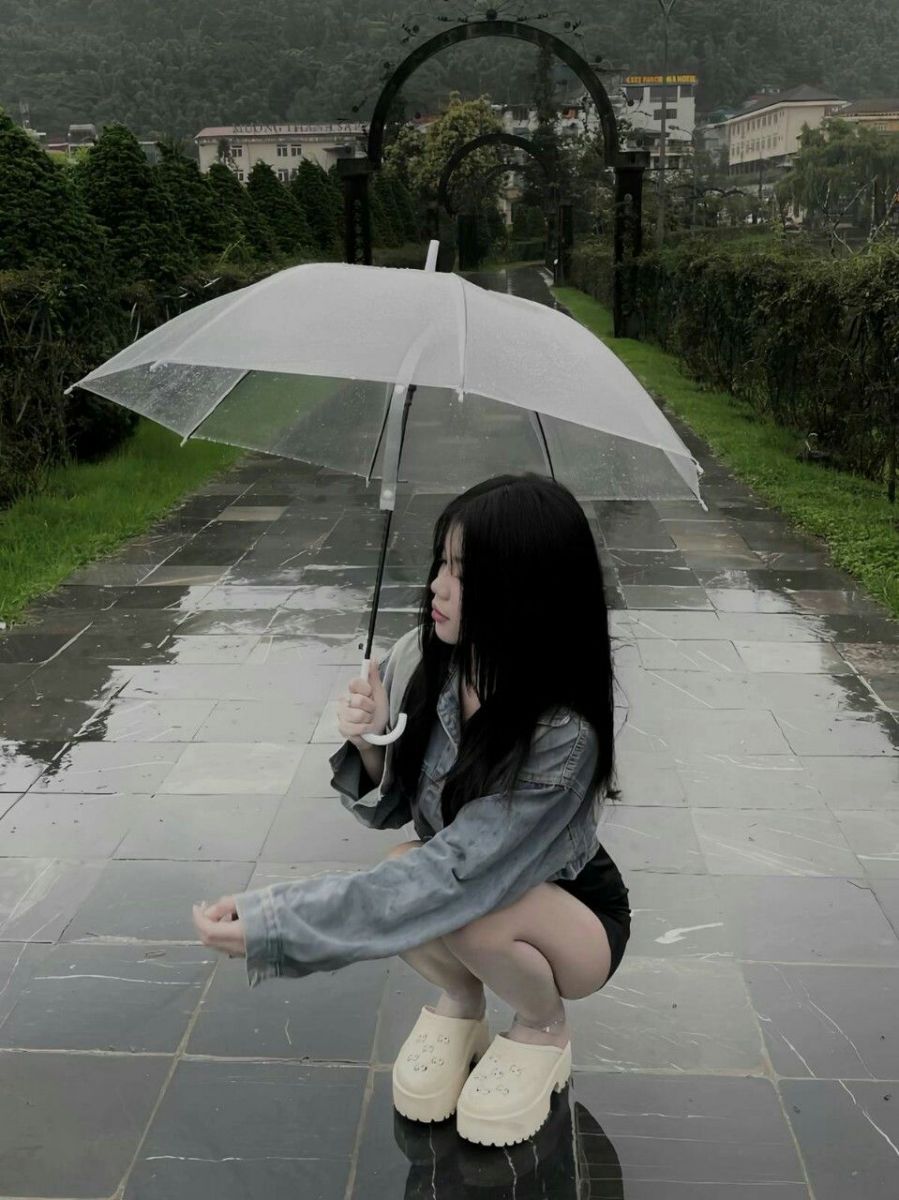 Cô gái xinh mặc áo khoác denim và quần short ngồi trên vỉa hè