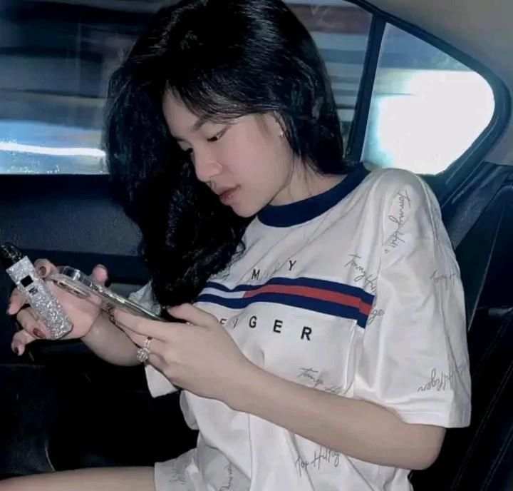 Cô gái xinh mặc áo phông trắng, ngồi trong xe với điện thoại