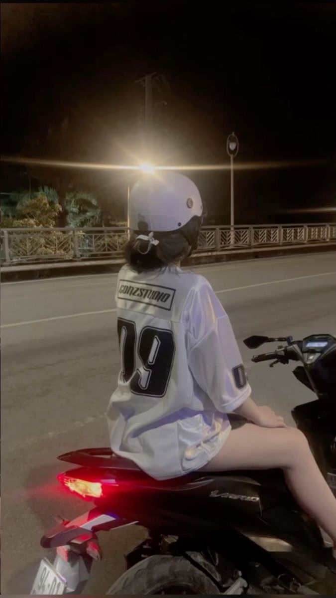 Cô gái xinh mặc áo thun bóng đá màu trắng bên xe máy