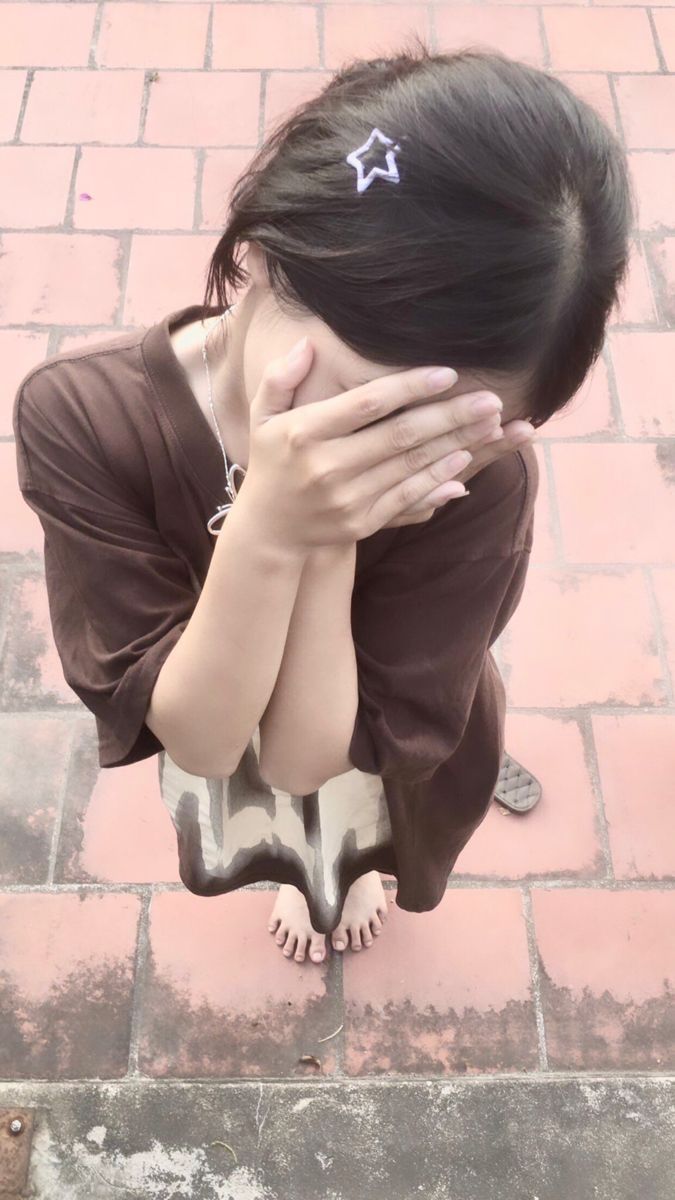 Gái che mặt trong áo phông nâu và váy hoa trên nền gạch đỏ