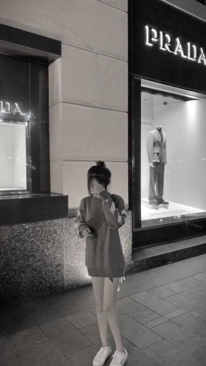 Gái che mặt trong áo sweater xám trước cửa hàng Prada