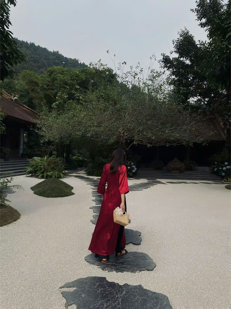 Gái đẹp mặc áo dài đỏ đi bộ trên lối đá xanh