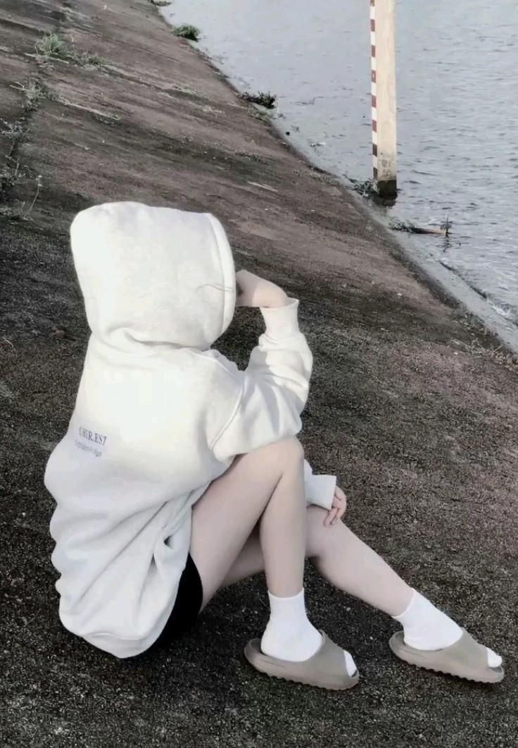 Gái đẹp trong áo hoodie trắng và quần short đen bên bờ sông