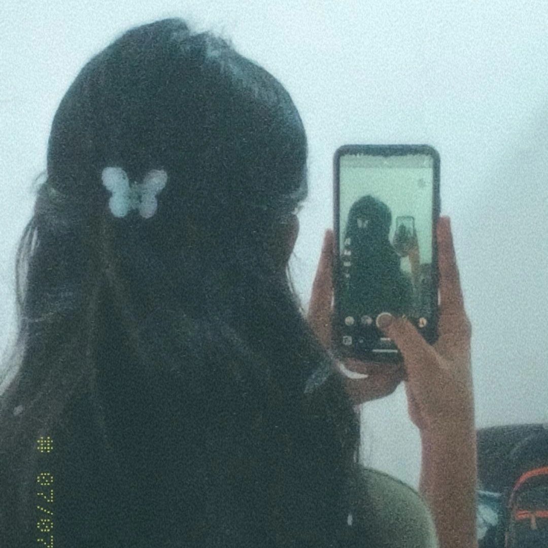 Gái trẻ mặc áo đơn giản chụp ảnh selfie trong phòng có gương