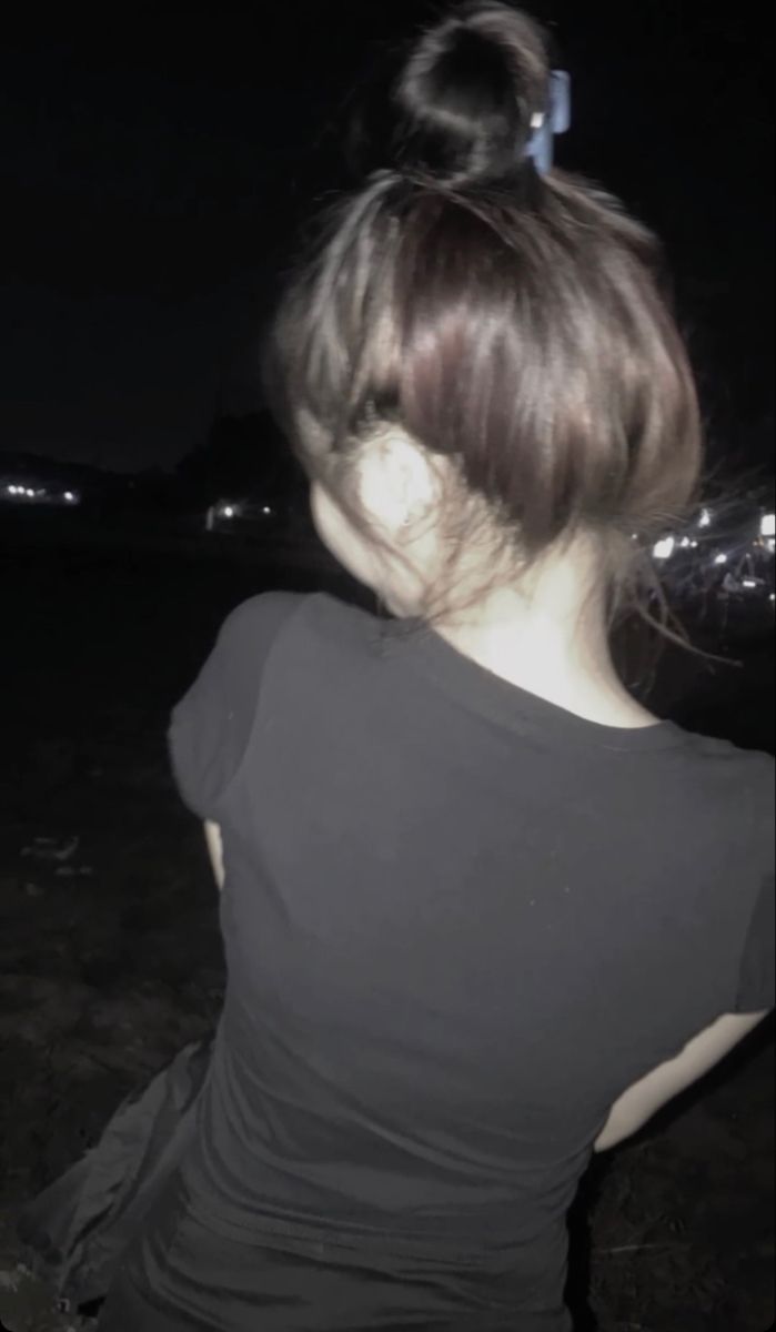 Gái trẻ mặc áo phông đen, đứng quay lưng ở nơi tối tăm