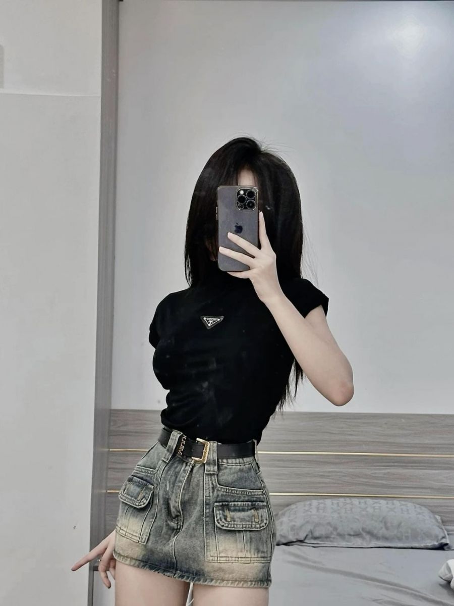 Gái trẻ mặc áo phông đen và chân váy denim chụp ảnh selfie trong gương