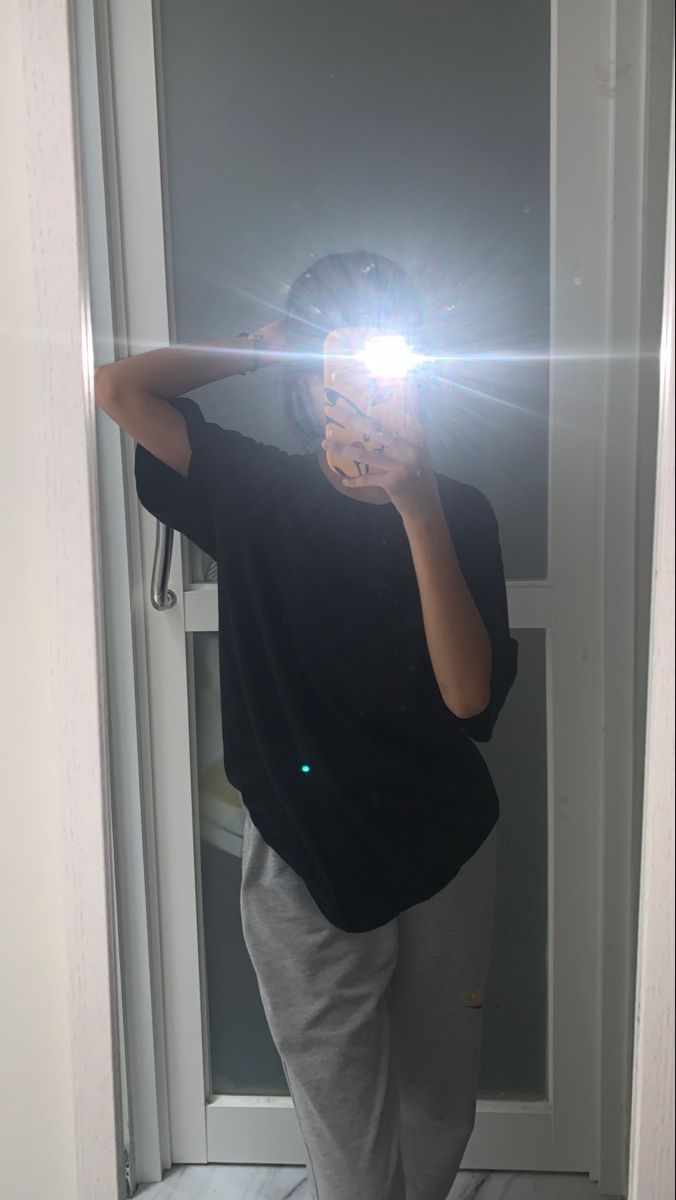 Gái trẻ mặc áo phông đen và quần thể thao xám chụp ảnh selfie tại nhà