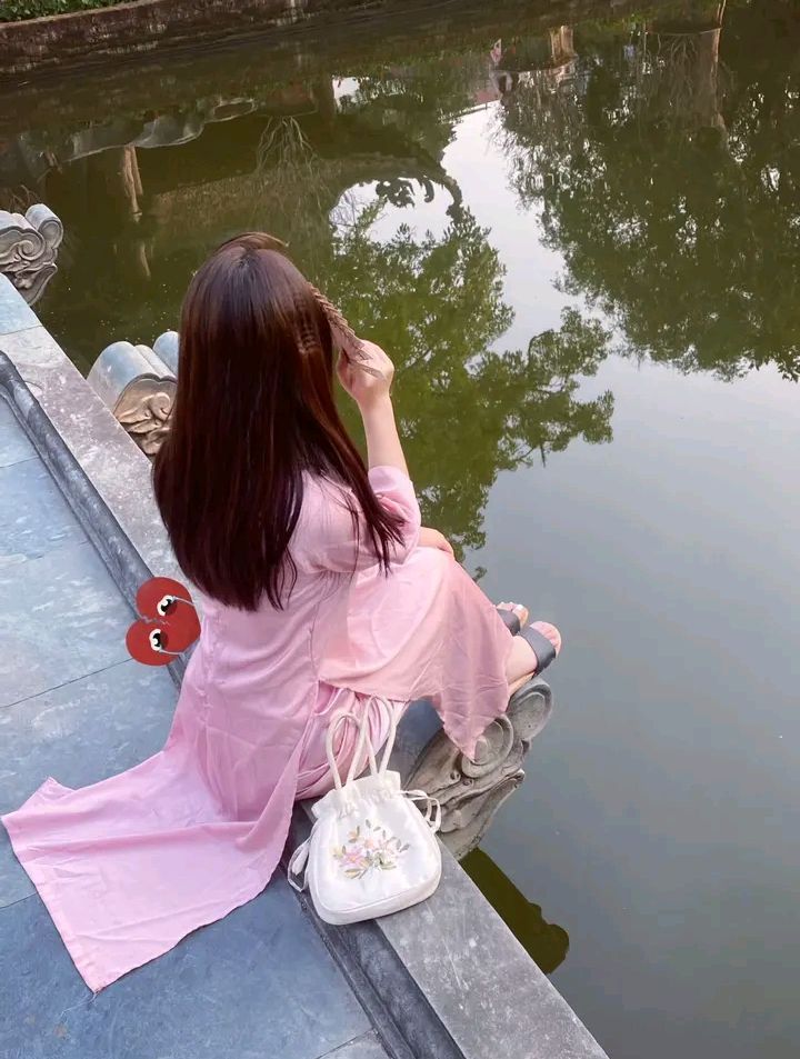 Gái xinh đẹp trong áo dài màu hồng bên hồ nước yên tĩnh