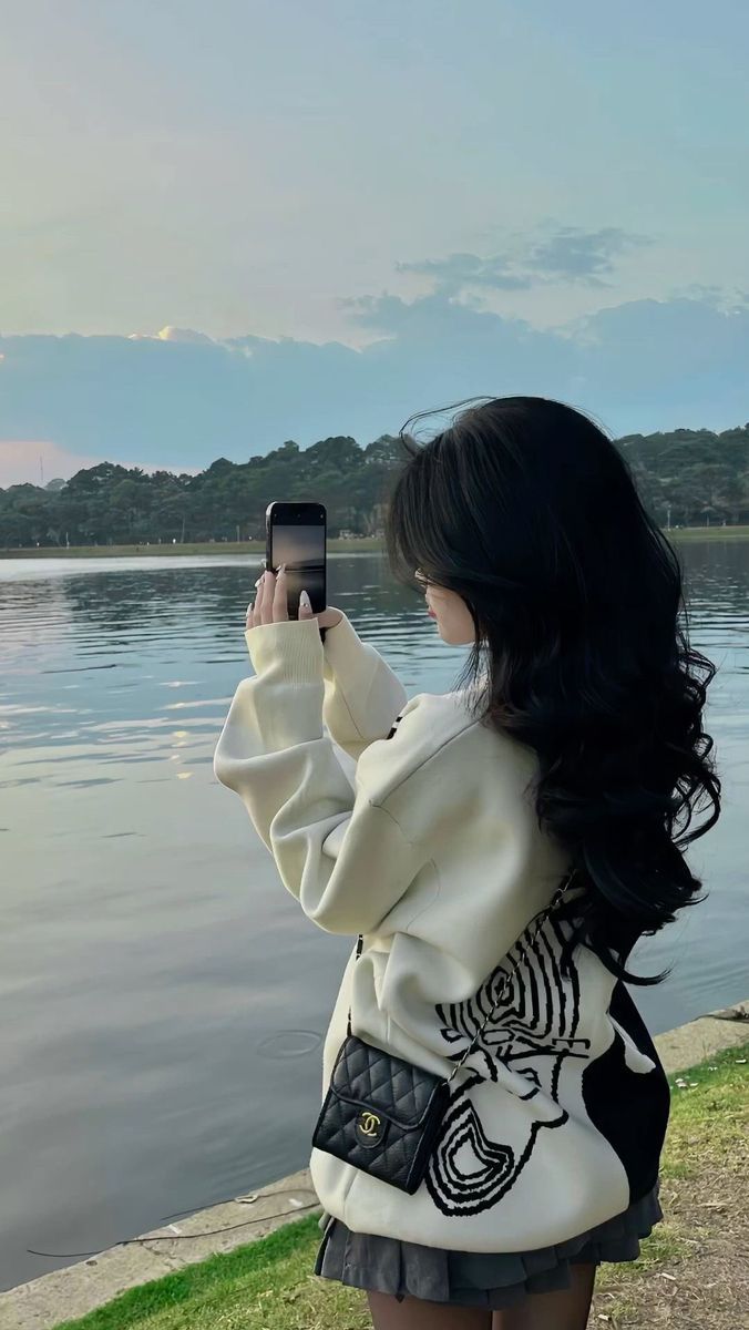 Gái xinh diện áo sweater trắng và chân váy đen bên hồ