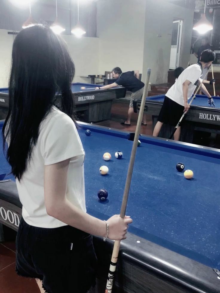 Gái xinh diện áo trắng và quần shorts đen chơi bi-a