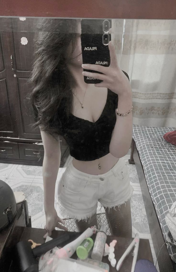 Gái xinh mặc áo croptop đen và quần shorts trắng chụp selfie