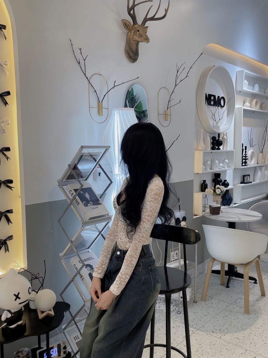 Gái xinh mặc áo dài và quần jeans trong quán cà phê hiện đại