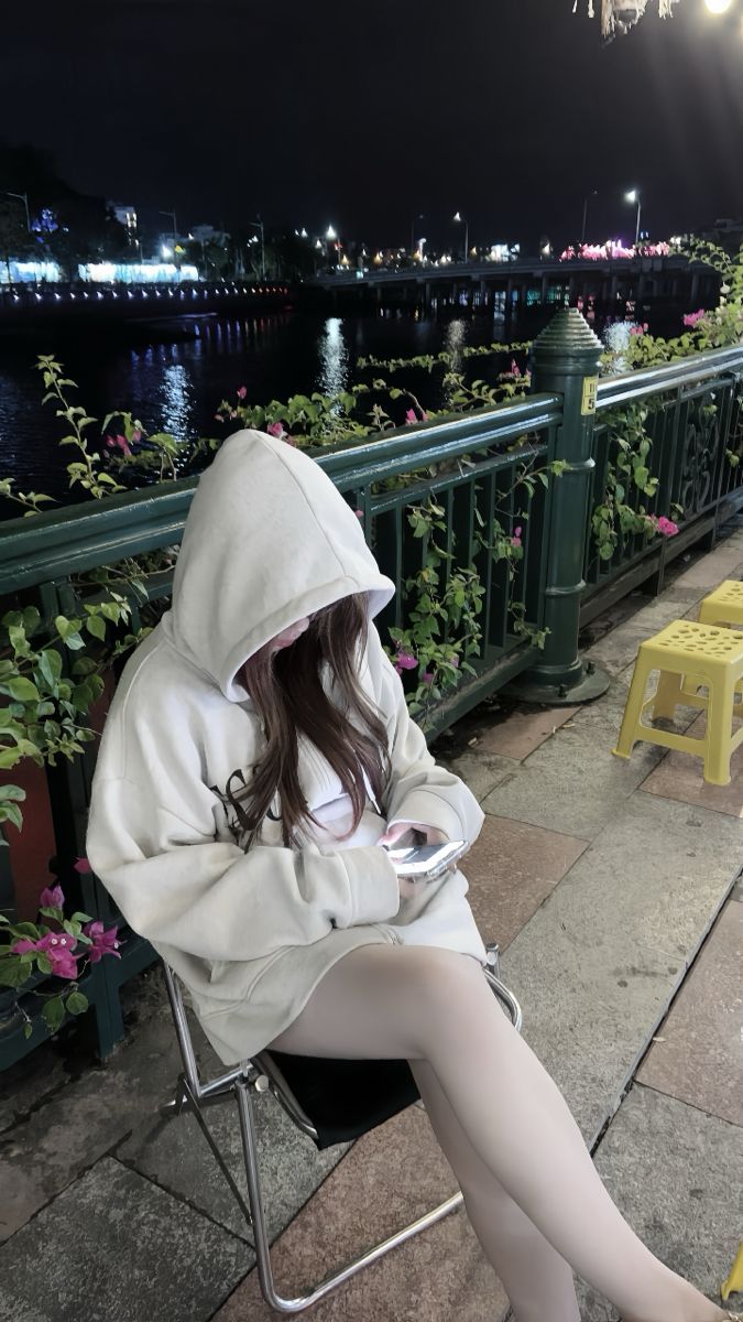Gái xinh mặc áo hoodie trắng ngồi bên bờ sông