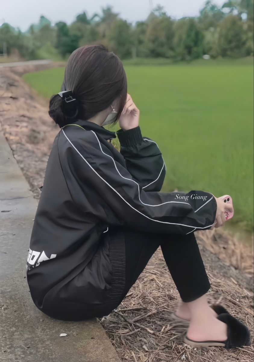 Gái xinh mặc áo khoác đen và quần legging bên cánh đồng xanh