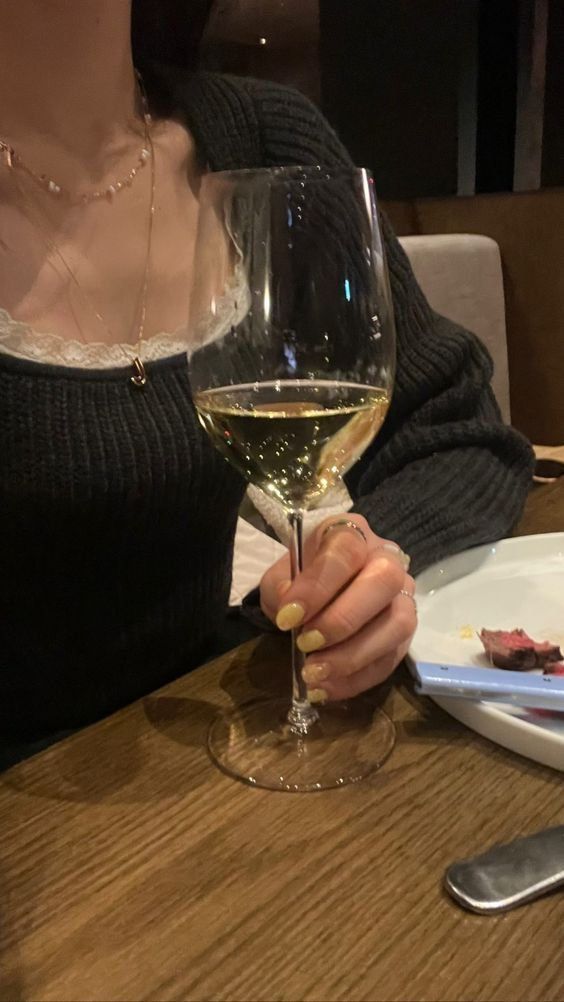 Gái xinh mặc áo len tông màu cam lỳ và rượu vang trắng trong nhà hàng sang trọng