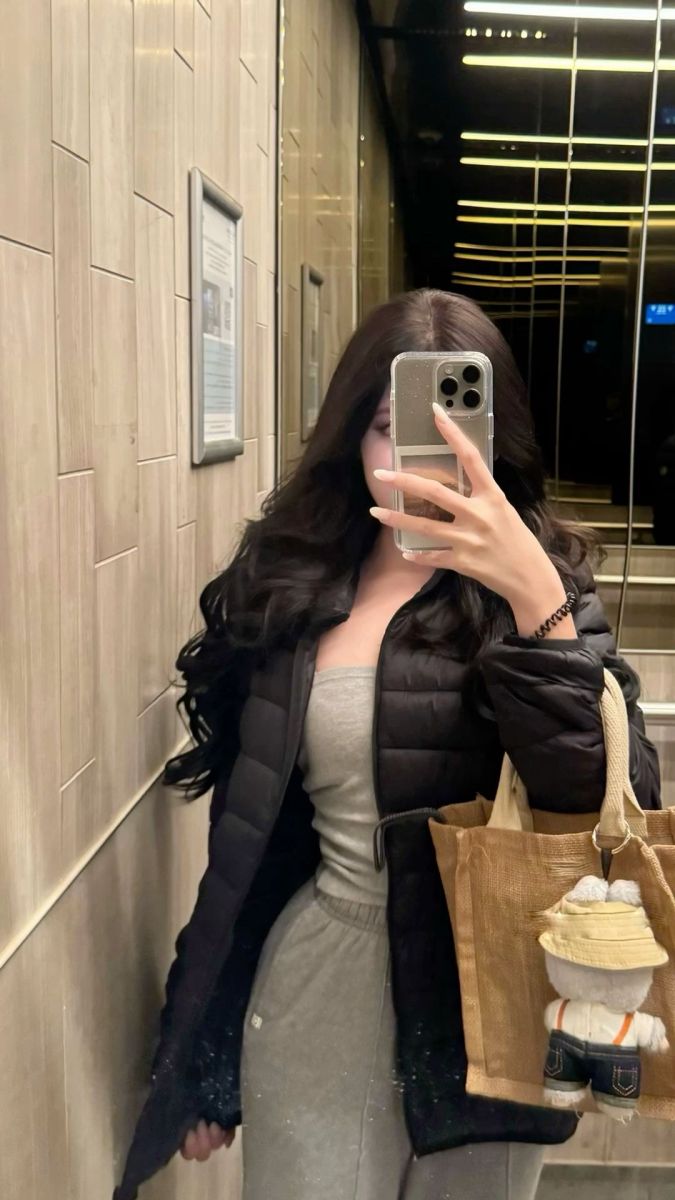 Gái xinh mặc áo phao đen và bộ đồ thể thao xám trong thang máy