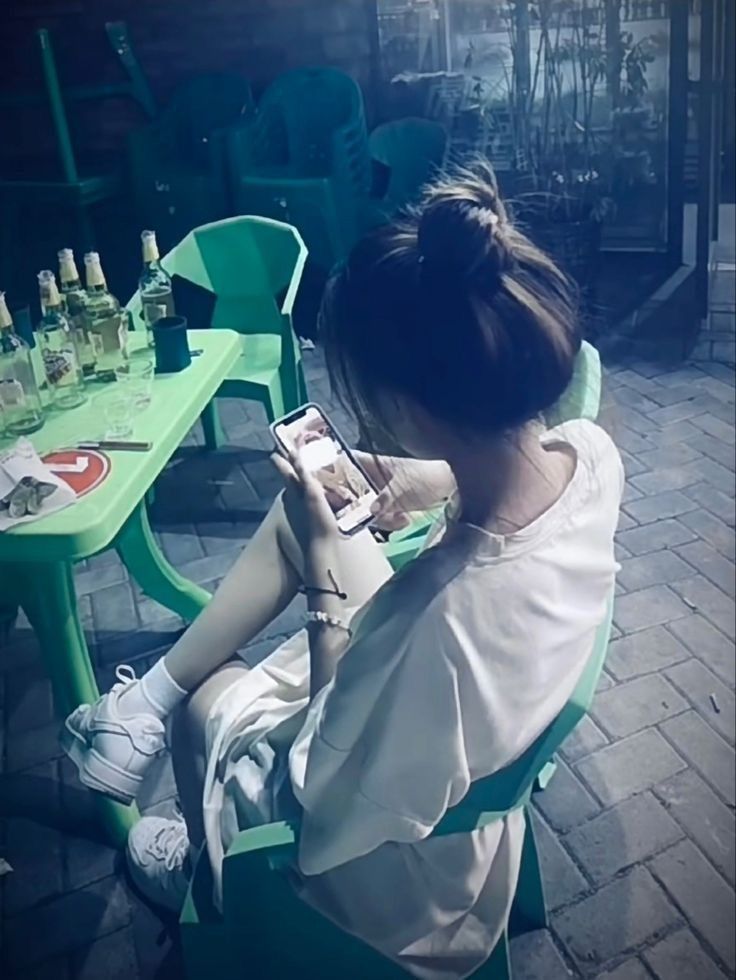 Gái xinh mặc áo sơ mi dài ngồi trên ghế nhựa màu xanh cam