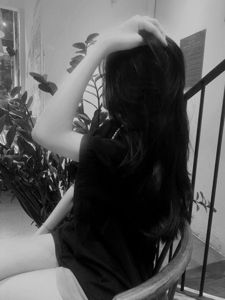 Gái xinh mặc áo sơ mi đen ngồi trên ghế gỗ trong quán cà phê