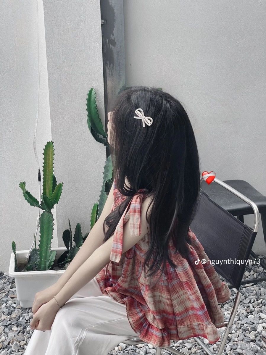 Gái xinh mặc áo sơ mi kẻ caro và quần trắng ngồi trên ghế
