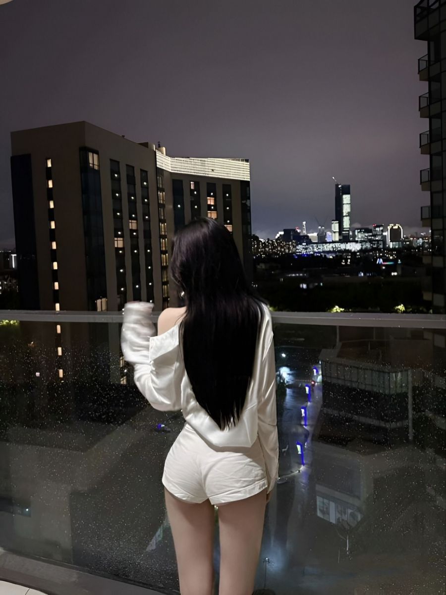 Gái xinh mặc áo sơ mi trắng và quần shorts nhìn ra thành phố