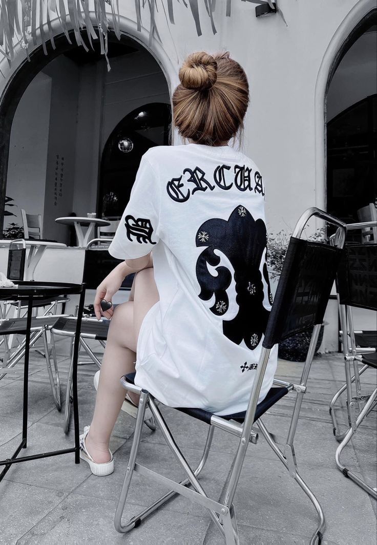 Gái xinh mặc áo thun trắng hoa tiết ngồi trên ghế xếp