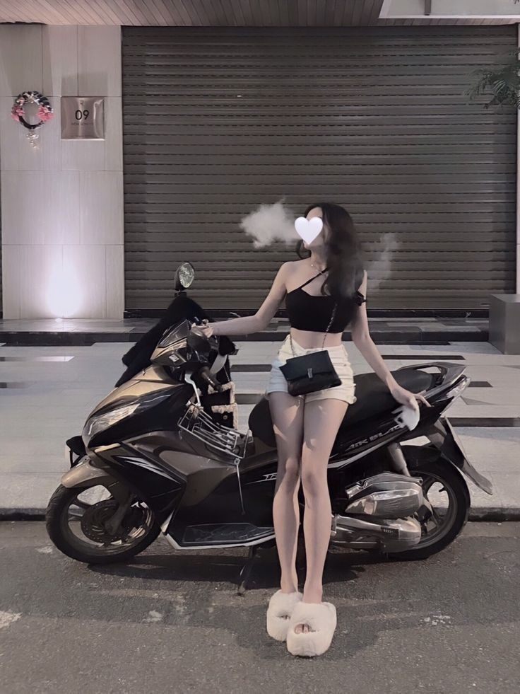 Gái xinh mặc croptop đen và quần short trắng bên xe máy