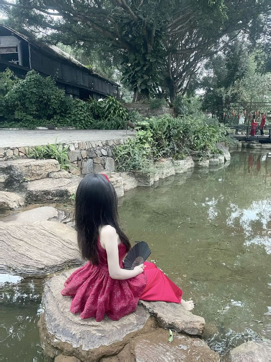 Gái xinh mặc đầm đỏ ngồi bên hồ cam quýt yên bình