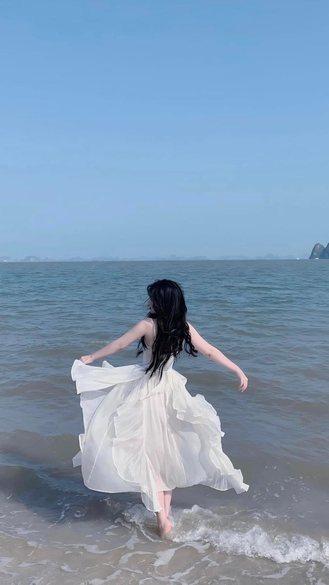 Gái xinh mặc váy trắng chạy trên biển, cảm thấy tự do và vui vẻ