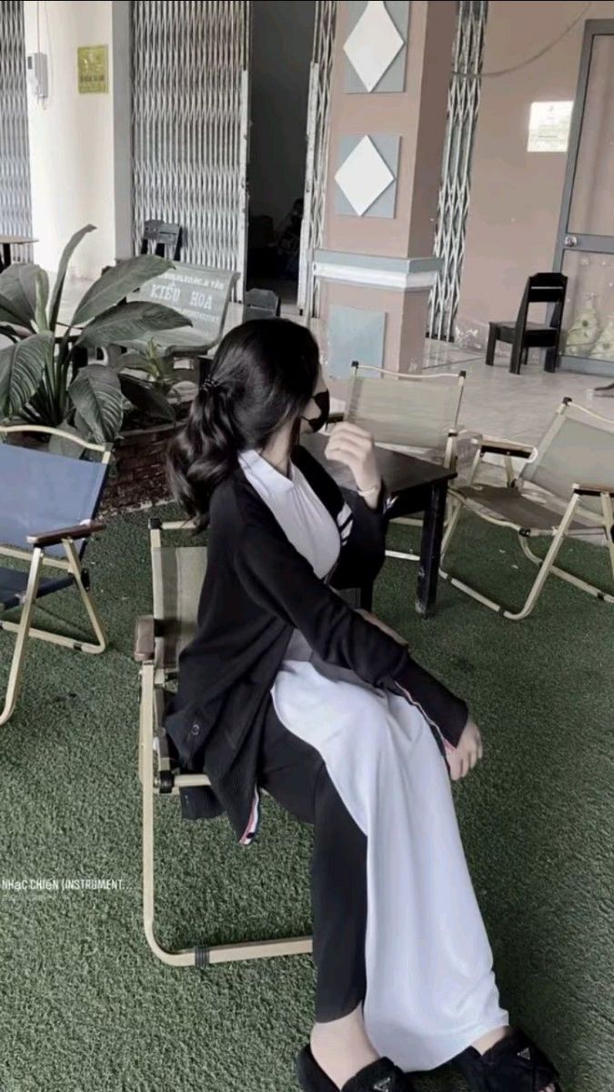 Gái xinh trong áo dài trắng và áo khoác đen bên cây xanh