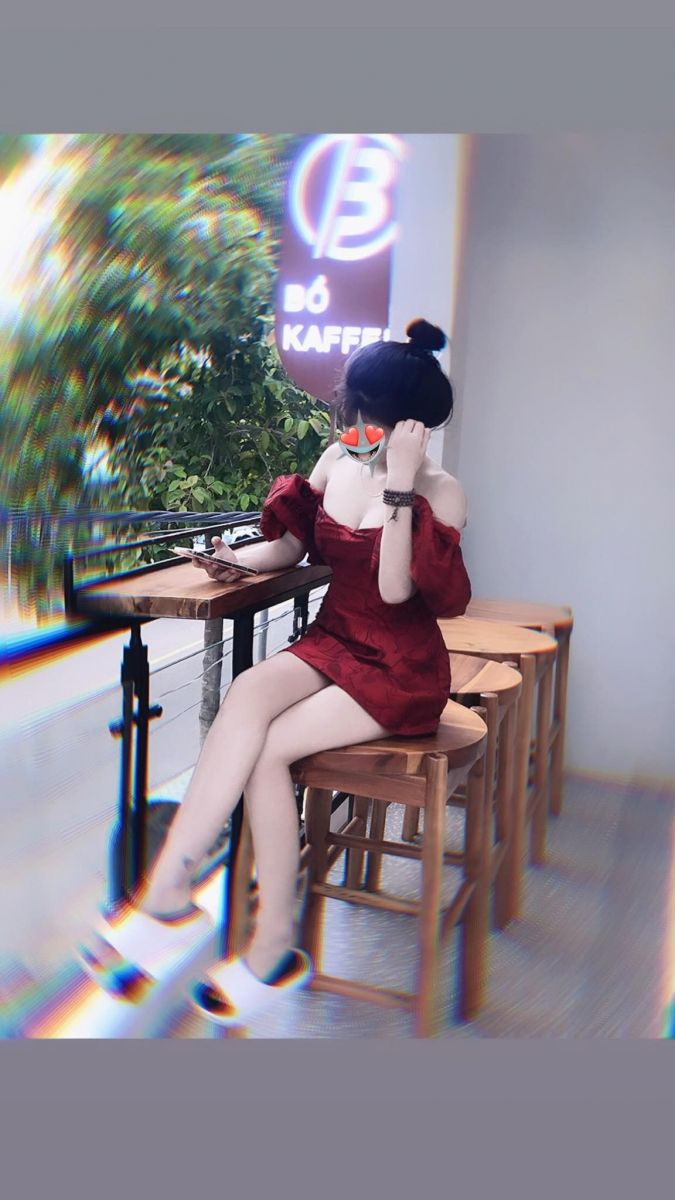 Gái xinh tự tin ngồi trên ghế gỗ với điện thoại