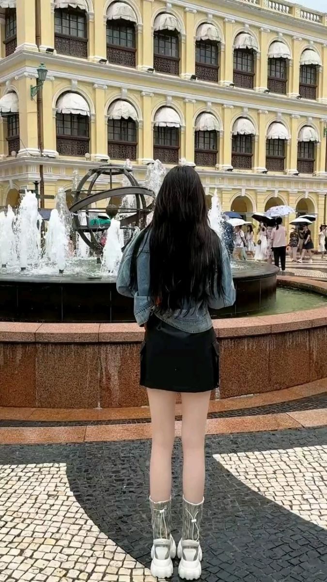 Gái xinh với áo khoác denim và chân váy ngắn tạo dáng bên đài phun nước