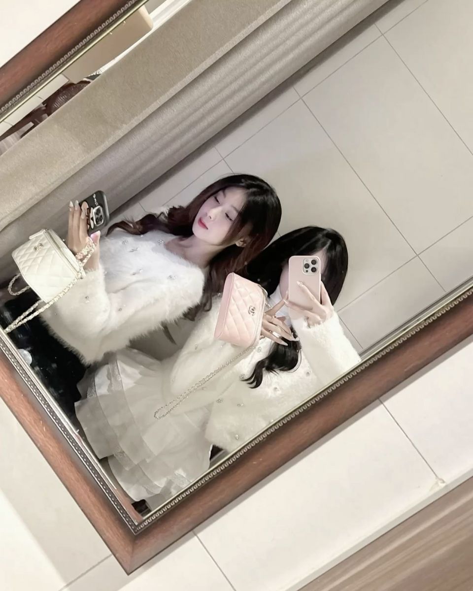Hai cô gái trẻ chụp ảnh selfie với áo khoác trắng và chân váy trắng