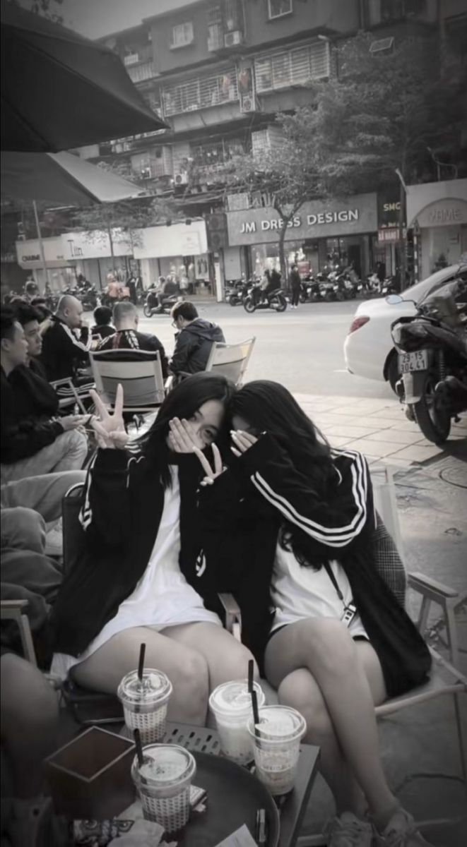 Hai cô gái trẻ mặc áo khoác đen và áo trắng tại quán cà phê