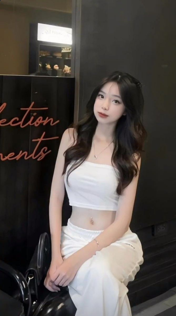 Ảnh gái trẻ mặc áo crop top trắng và quần trắng tự tin trên ghế
