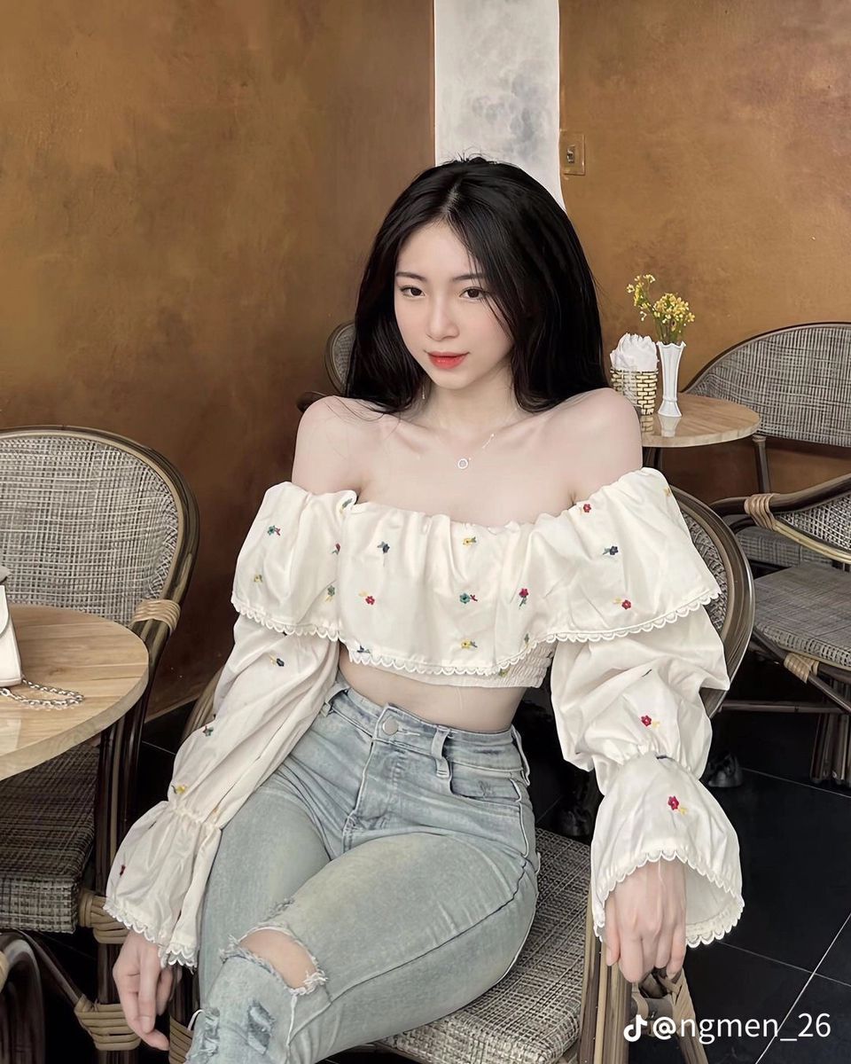Ảnh gái trẻ mặc áo croptop voan trắng hoa văn ngồi trong quán cà phê