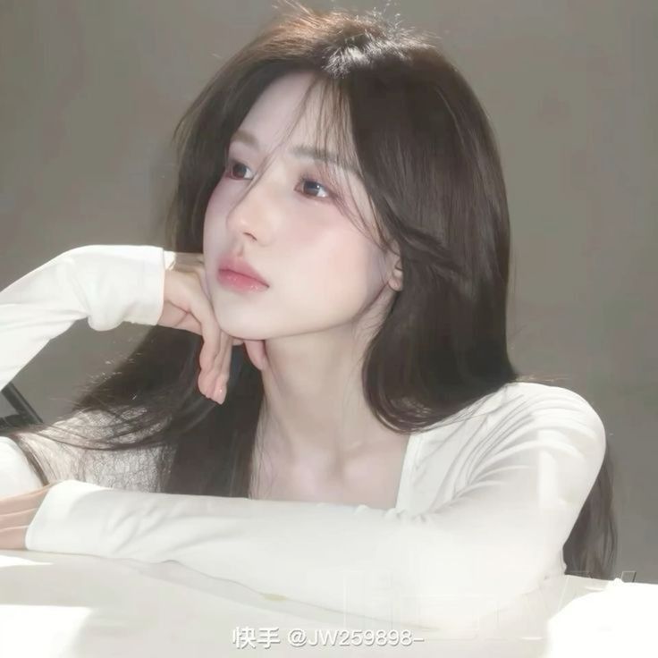 Ảnh gái trẻ mặc áo dài tay trắng ngồi tửa tay lên bàn trong không gian ánh sáng nhẹ nhàng
