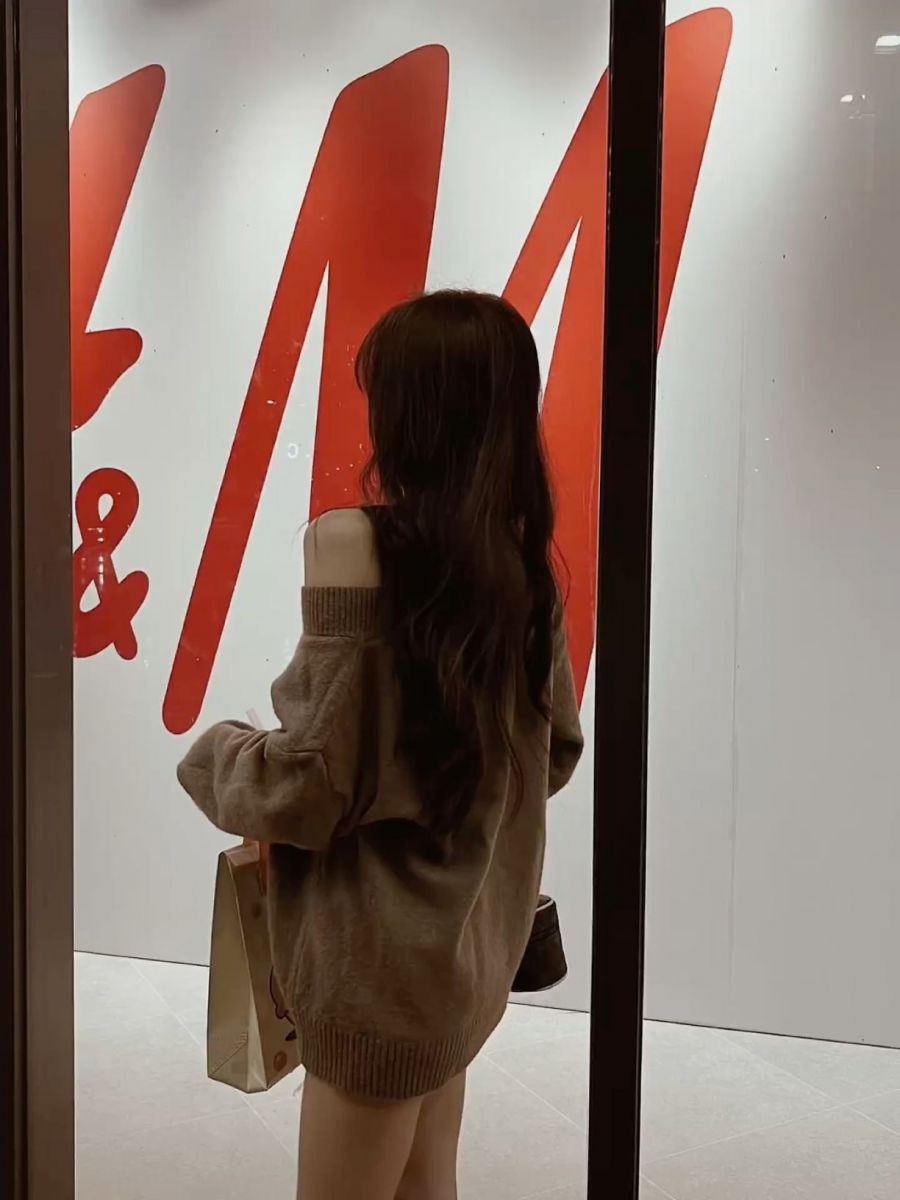 Ảnh gái trẻ mặc áo len oversize bên ngoài cửa hàng H&M