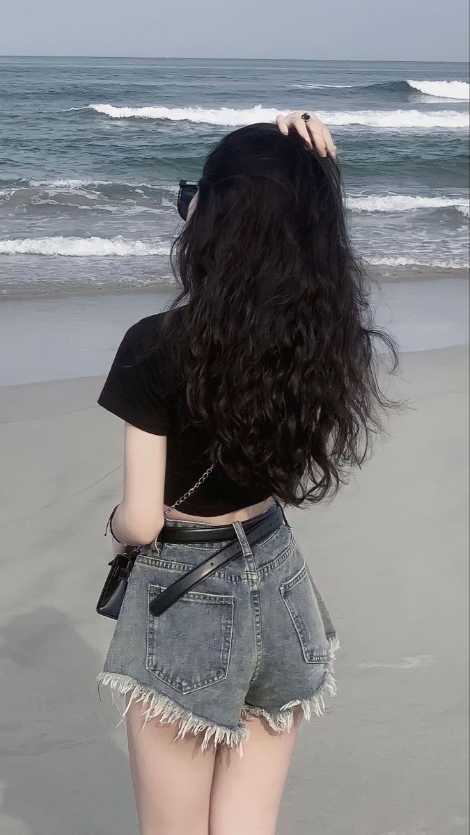 Ảnh gái xinh mặc áo thun đen và quần short jeans bên bờ biển
