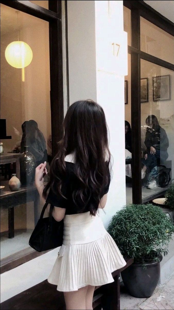 Cô gái bên cửa sổ với áo phông đen và chân váy xếp ly