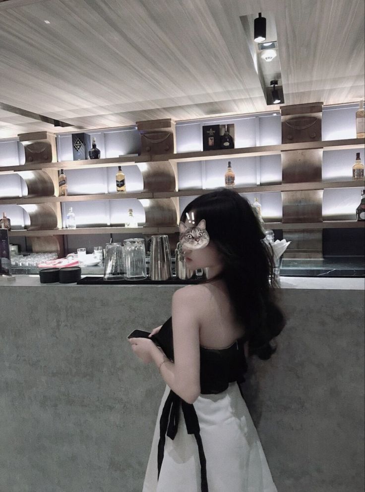 Cô gái mặc áo không tay màu đen và chân váy trắng bên quầy bar