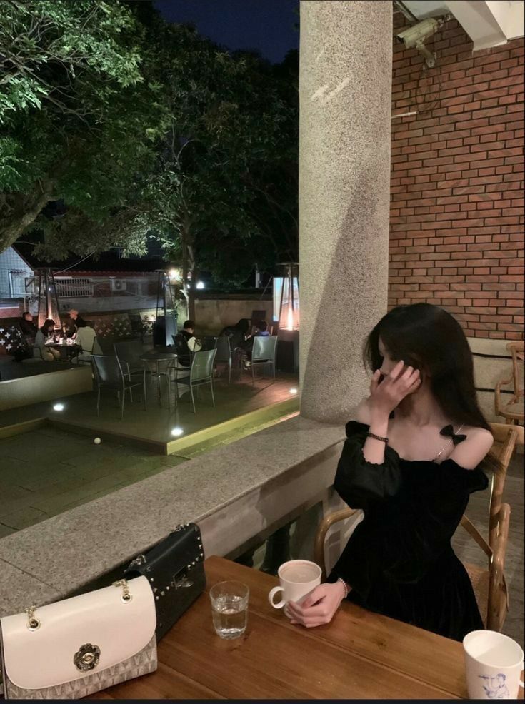 Cô gái mặc váy đen ngồi ở quán cà phê đêm