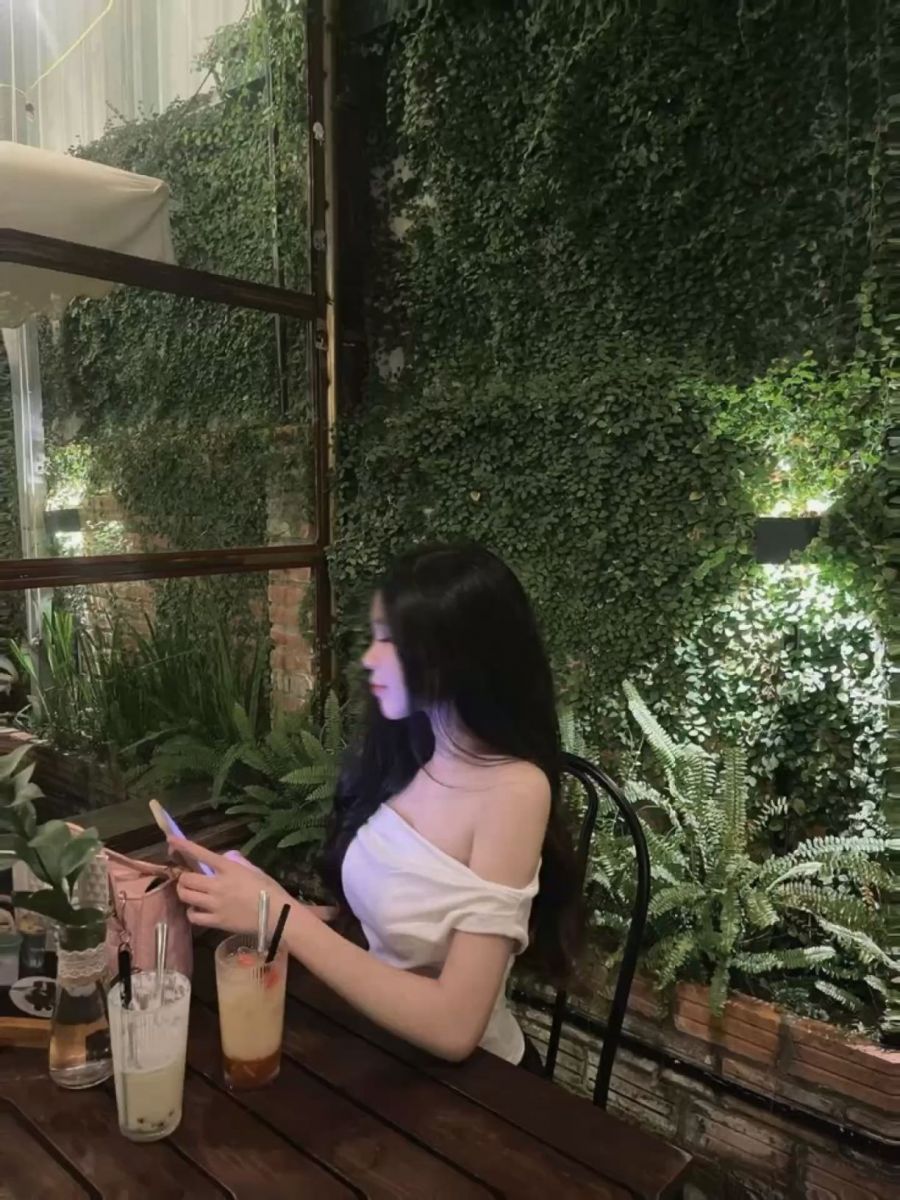 Cô gái ngồi tại quán cà phê với áo trắng cam