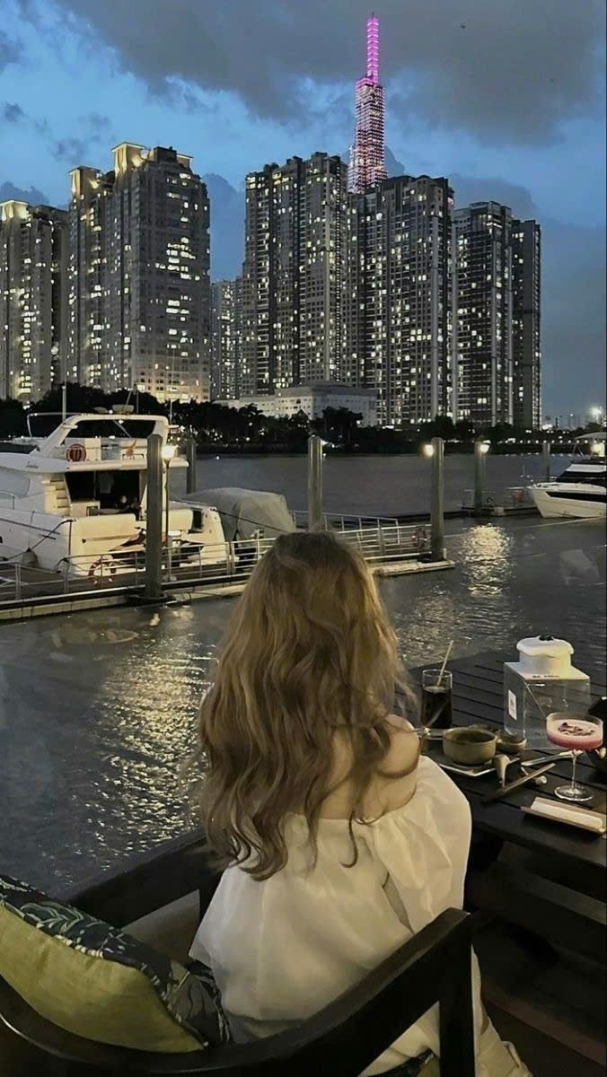 Cô gái tóc dài mặc áo trắng ngồi trên ghế quán cà phê