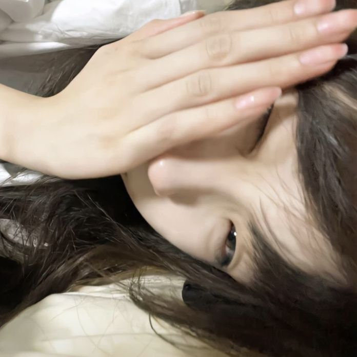 Cô gái trẻ che mặt bằng áo phông trắng trên giường