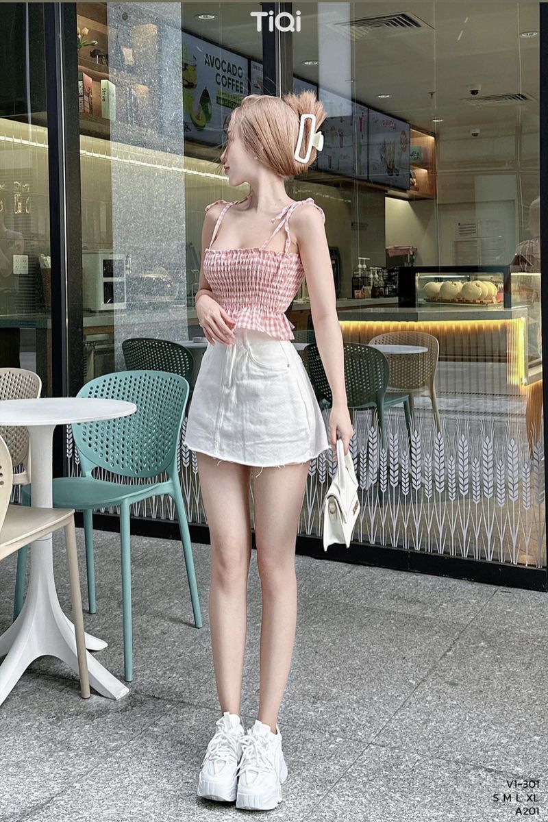 Cô gái trẻ mặc áo crop top hồng và chân váy trắng