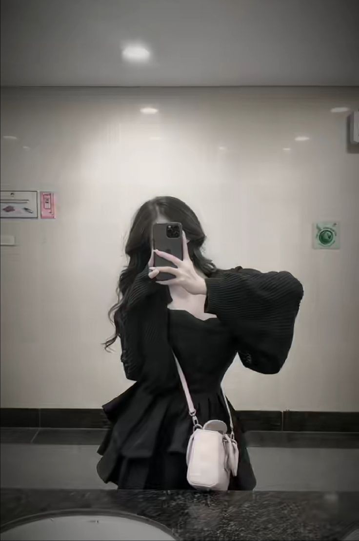 Cô gái trẻ mặc áo đen chụp selfie trong gương phòng vệ sinh
