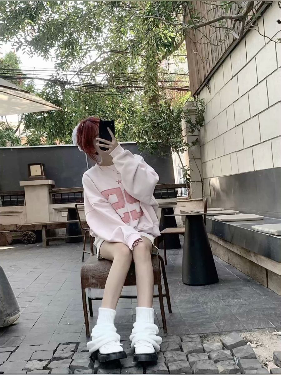Cô gái trẻ mặc áo hoodie hồng và quần short chụp ảnh tự sướng