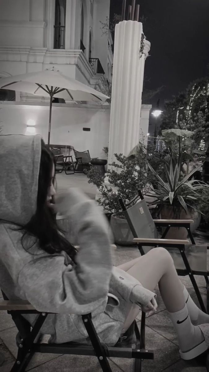 Cô gái trẻ mặc áo hoodie xám ngồi trên ghế gỗ